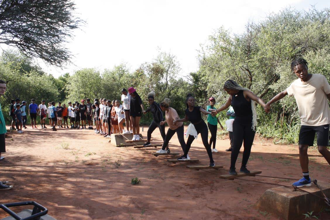 A school group in a team activity on the grass at Camp Wildside
